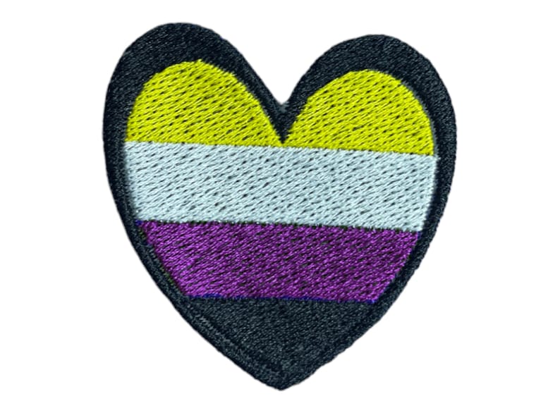May include: A heart-shaped embroidered patch with the colors of the non-binary pride flag: yellow, white, purple, and black.