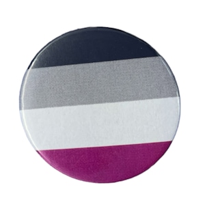 Op de afbeelding: Een ronde knop met een zwart, grijs, wit en paars gestreept ontwerp. De knop is een representatie van de asexuele pride-vlag.
