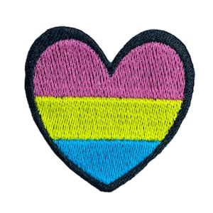 Peut inclure: Un patch brodé en forme de cœur rose, jaune et bleu avec un contour noir.