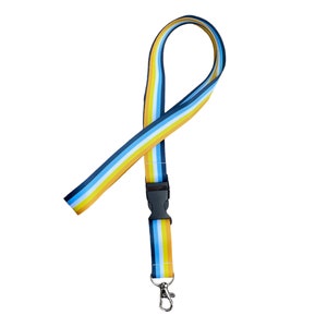 Può includere: Un laccio blu, giallo e bianco a righe con un fermaglio in plastica nera e un gancio girevole argentato.