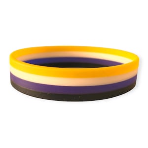 Könnte beinhalten: Ein mehrfarbiges Silikonarmband mit vier Streifen: Gelb, Weiß, Lila und Schwarz.