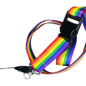 Op de afbeelding: Een regenboog lanyard met een zwarte plastic clip en een afneembare telefoonriem. De lanyard is gemaakt van een zachte, geweven stof.