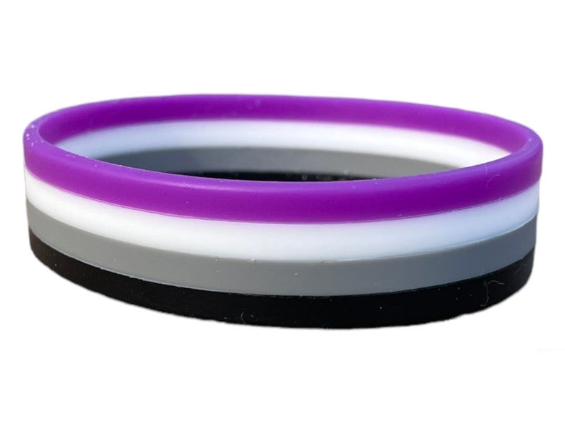 May include: A black, gray, white, and purple silicone bracelet. The bracelet is a symbol of the asexual pride flag.