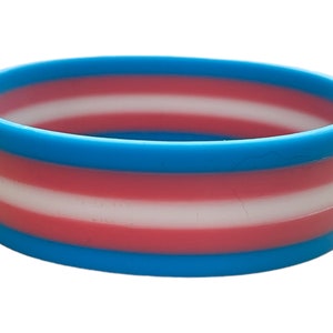 May include: A blue, pink and white silicone bracelet with the transgender pride flag colours.