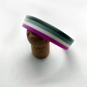 May include: A multi-colored silicone bracelet with stripes of purple, white, gray, and black.