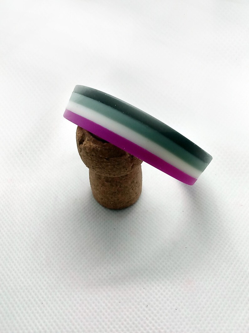 May include: A multi-colored silicone bracelet with stripes of purple, white, gray, and black.