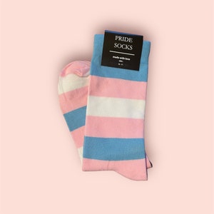 May include: A pair of blue, pink and white striped socks with a black tag that reads "PRIDE SOCKS made with love 36-41".