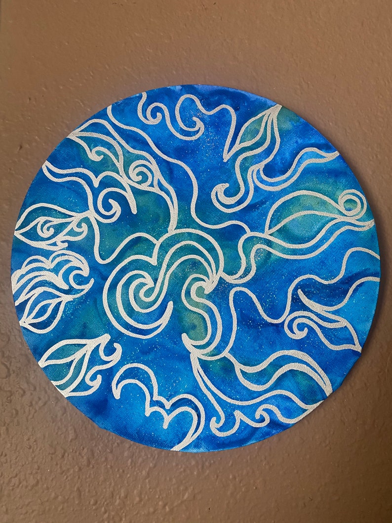 Pu&ograve; includere: Una tela rotonda dipinta di blu e bianco con un design astratto a spirale. Il design ricorda le onde o le nuvole.