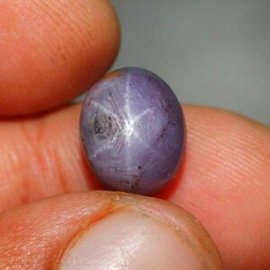 Könnte beinhalten: Ein violetter Stern-Saphir-Edelstein mit einem sternförmigen Muster in der Mitte.