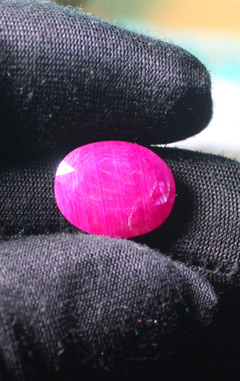 K&ouml;nnte beinhalten: Ein leuchtend rosa ovaler Edelstein mit einer glatten, polierten Oberfl&auml;che. Der Edelstein hat ein subtiles, gestreiftes Muster.