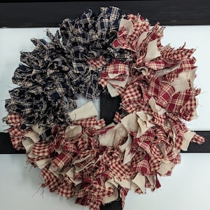 May include: A red, white and blue fabric wreath with a gingham pattern. The wreath is made of fabric scraps and is perfect for a patriotic display.