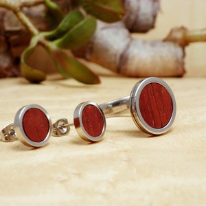 May include: Three pairs of stainless steel earrings with red wood inlay. The earrings are in different sizes.