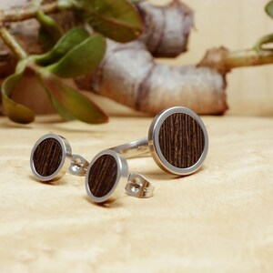 May include: A set of three silver rings with dark wood inlays. The rings are round and have a simple design. The rings are perfect for a minimalist look.