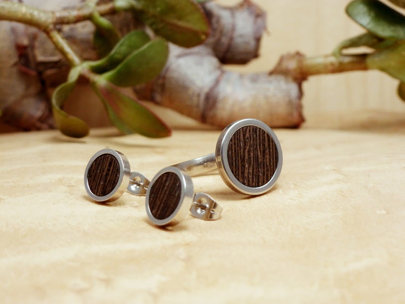 May include: A set of three silver rings with dark wood inlays. The rings are round and have a simple design. The rings are perfect for a minimalist look.