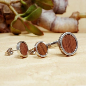 May include: Three round wood and silver earrings. The earrings are different sizes. The largest earring is about 1 inch in diameter.