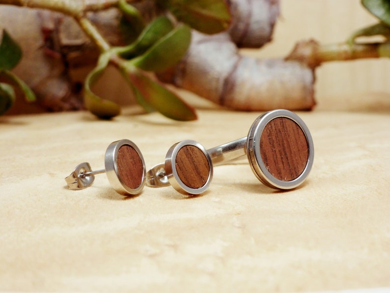 May include: Three round wood and silver earrings. The earrings are different sizes. The largest earring is about 1 inch in diameter.