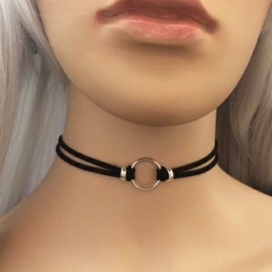 May include: A black choker necklace with a silver ring accent. The choker is made of two thin black cords.