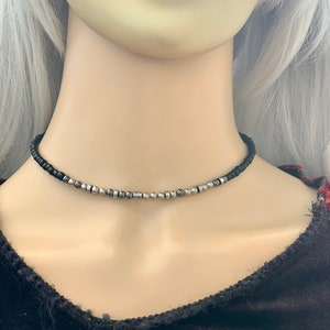 May include: A black choker necklace with silver and black beads.
