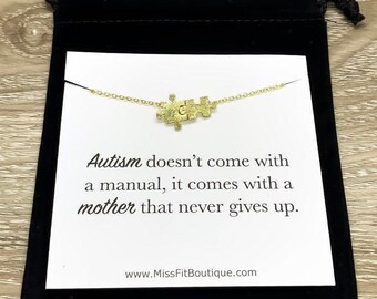 May include: A gold necklace with a puzzle piece charm on a white card with the text "Autism doesn't come with a manual, it comes with a mother that never gives up." and the website address "www.MissFitBoutique.com".