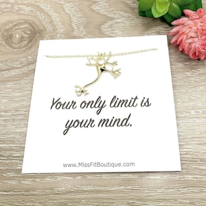 May include: A white card with the text "Your only limit is your mind." and the website address "www.MissFitBoutique.com". A gold necklace with a neuron pendant is displayed on the card.