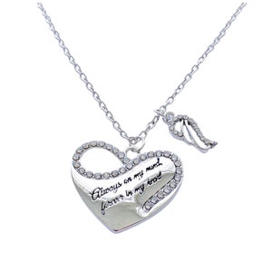 Puede incluir: Collar de plata con un colgante en forma de corazón que dice "Always on my mind, forever in my heart". El colgante en forma de corazón está adornado con brillantes de cristal y tiene un pequeño amuleto de ala de ángel.