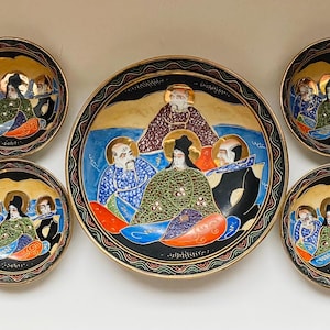 May include: A collection of eight decorative ceramic plates. The plates depict a religious scene with gold, blue, green, and orange details. The plates are arranged on a white surface.