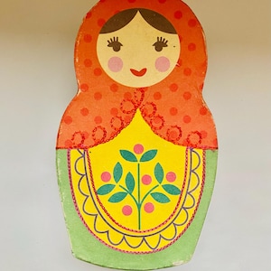 May include: A colourful, vintage-style Matryoshka doll. The doll features a red polka-dot head covering, a yellow apron with a floral design, and a green base. The design is reminiscent of traditional Russian folk art.