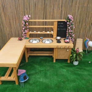 Può includere: Una cucina giocattolo in legno con un lavandino, un piano cottura e degli scaffali. La cucina è dipinta di marrone e ha un cartello in lavagna che dice "Because Little Treasures".
