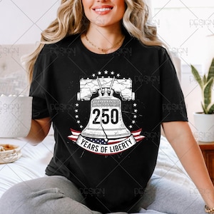 Puede incluir: Camiseta negra con un gr&aacute;fico de la Campana de la Libertad, el n&uacute;mero 250 y el texto "Years of Liberty". El dise&ntilde;o incluye estrellas y una pancarta con la bandera americana.