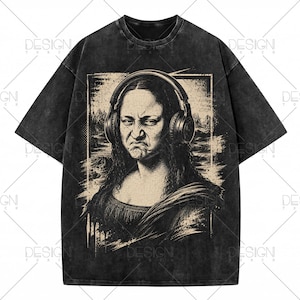 Może przedstawiać: Czarny t-shirt z efektem sprania, ozdobiony grafiką przedstawiającą osobę z długimi ciemnymi włosami w dużych słuchawkach nausznych. Postać ma skrzywioną minę i znajduje się na tle o fakturze szkicu, zamkniętym w prostokątnej ramce.