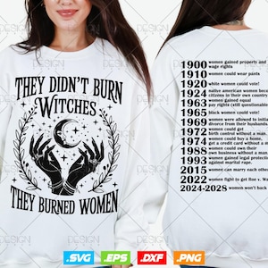 以下が含まれることがあります： 「THEY DIDN'T BURN WITCHES THEY BURNED WOMEN」の黒い文字が入った白いスウェットシャツ。デザインには三日月、星、手が含まれています。シャツの背面には、女性の権利のマイルストーンがリストされています。