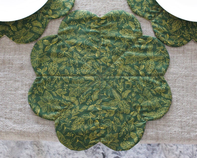 May include: A green and gold floral patterned table runner with a scalloped edge.