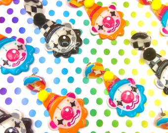 May include: A set of colorful clown-themed earrings with black and white checkered patterns. The earrings are made of polymer clay and have a glossy finish.