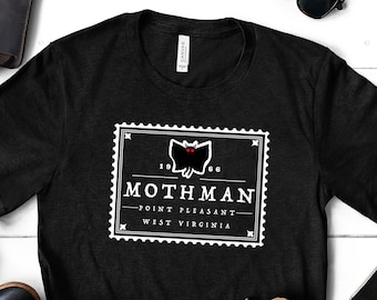 May include: Black t-shirt with a white graphic of a moth with red eyes and the text "Mothman - Point Pleasant - West Virginia".