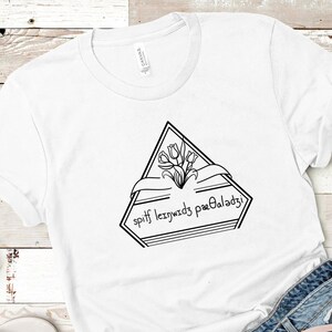 May include: White t-shirt with a black graphic design of a triangle with a bouquet of flowers and the text "spiff leizywidz paeOaladzj".