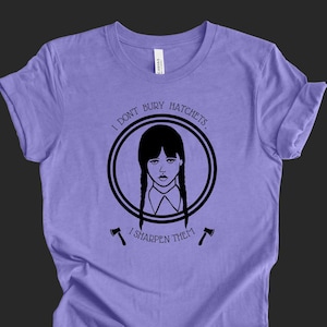 May include: Purple t-shirt with a black and white graphic of a girl with pigtails and the text "I don't bury hatchets. I sharpen them."