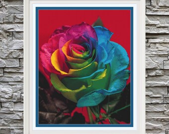 May include: A single rainbow rose with petals in shades of red, orange, yellow, green, blue, and purple. The rose is in focus against a red background.