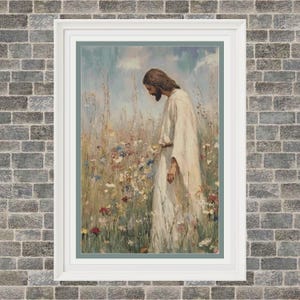 May include: A framed print depicts a figure in a white robe, with long brown hair and a beard, standing in a field of wildflowers. The artwork has a soft, painterly style with a muted color palette, framed in a white border.