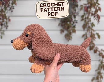 May include: A brown and tan plush dachshund toy made of chunky yarn with black eyes and a black nose. Above the toy, a white sign with rounded corners features the dark brown text CROCHET PATTERN PDF in a bold, sans-serif font.