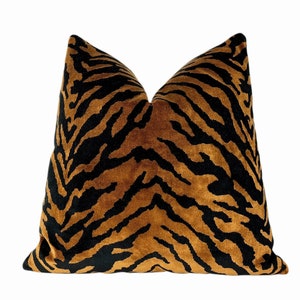 May include: A decorative pillow with a tiger stripe pattern. The pillow features a brown and black design, with the black stripes contrasting against the brown background. The pillow is square and has a soft, plush appearance.