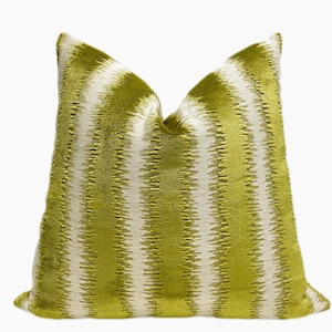 May include: A decorative pillow with a lime green and white striped pattern. The pillow has a soft, textured appearance and a square shape. The stripes run vertically across the pillow's surface, creating a visual texture. The pillow is a home decor item.