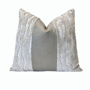 May include: A gray and white decorative pillow with a textured fabric. The pillow has a center panel of a different fabric.
