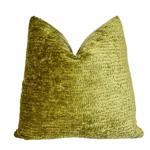 May include: A large, square decorative pillow in a vibrant olive green hue. The pillow has a textured, woven appearance, creating a plush and inviting aesthetic. The pillow is designed for home decor.