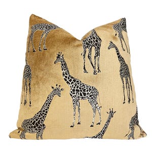 May include: A gold velvet pillow with a black and white giraffe print. The pillow features multiple giraffes in various poses.