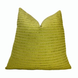 May include: A green throw pillow with a textured, striped pattern. The pillow is made of a soft, woven fabric.
