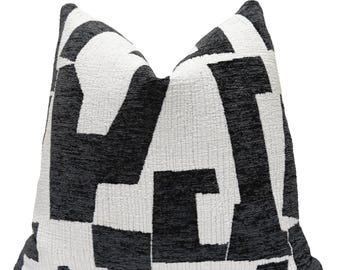 May include: A decorative throw pillow with a geometric pattern. The pillow features a repeating design of black and white shapes, creating a modern and graphic look. The fabric has a textured appearance.