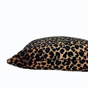 Puede incluir: Una almohada de tiro de color marr&oacute;n y negro con estampado de leopardo y un brillo sutil.