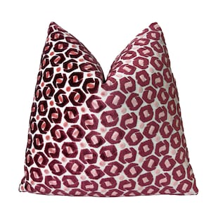 May include: A decorative throw pillow with a burgundy and pink leopard print pattern. The pillow has a soft, textured appearance and a white background. The leopard spots are in a repeating pattern across the pillow's surface.