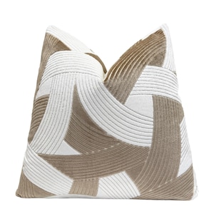 May include: A decorative throw pillow with a geometric pattern in beige and white. The pillow has a soft, plush texture and is perfect for adding a touch of modern style to any room.