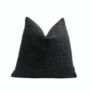 May include: A black, fluffy pillow with a textured surface.